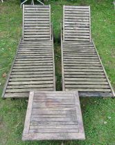 A pair of weathered teak portable garden loungers with slatted seats and adjustable head rests,