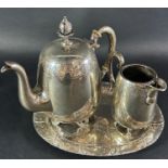 A breakfast tea service of a small silver plated engraved teapot, milk jug and a silver tray stamped