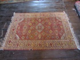 An eastern wool rug with red ground field central medallion and floral detail, within alternating