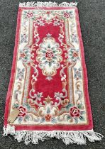 A pink Chinese deep pile wool carpet with a floral pattern 155 x 77cm approx and a circular