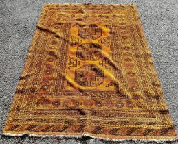 An Afghan carpet with a central row of elephant foot gul on a burnt orange ground 180 x 135cm approx