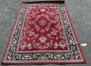 A modern machine made carpet with all over floral pattern on a red ground, 230cm x 160cm
