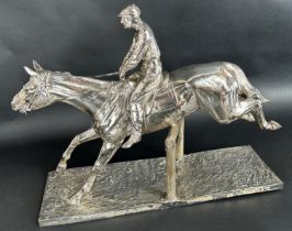 A large 20th century silver plated statuette of a race horse and jockey clearing a pole fence,