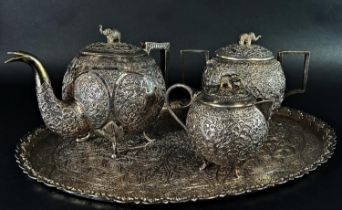 An Indian silver metal richly engraved three piece tea service with oval tray, 37 cm wide, 54.2