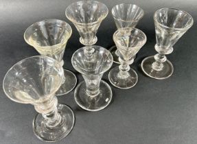 A selection of six similar Georgian baluster glasses with drawn trumpet bowls and a single glass