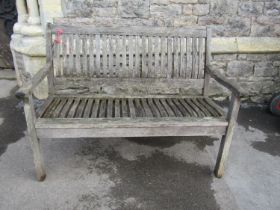A weathered teak two seat garden bench with curved slatted seat and back (labelled to back rail