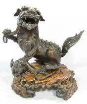 A 19th century Chinese bronze lion, toying with a cub, raised on a 'rocky' wooden stand, 23cm high