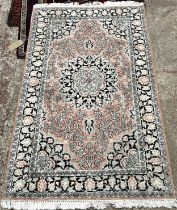 A Persian design rug with a central floral medallion on a pale pink floral ground, 158cm x 95cm