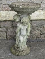 A weathered cast composition stone two sectional bird bath with circular top and standing hand in