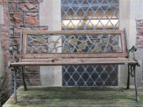 A weathered two seat garden bench with wooden slatted seat, pierced cast rose pattern back and