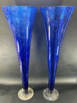 A pair of large blue flared trumpet vases with a clear circular foot, both standing one metre tall