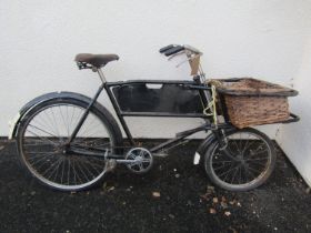 A vintage tradesman’s bicycle with front basket and vintage merchant’s board