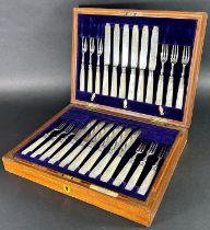 An oak canteen of silver bladed fruit knives and silver forks, all with mother-of-pearl handles, for