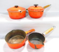 Two sunrise orange Le Creuset cast iron saucepans and two non stick cast iron saucepans without
