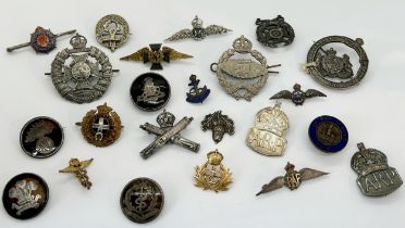 A collection of silver and other military cap badges, lapel badges, etc, some with tortoiseshell