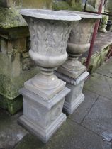A pair of cast composition stone classical style garden urns with flared rims and repeating leaf