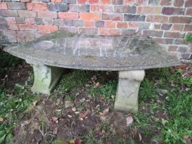 A weathered composition stone bench of curved form raised on scrolled acanthus supports, 43cm