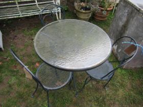 A weathered cast alloy circular garden terrace table (with loose glass top) together with three