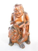 A carved wood figure of Buddha astride a lion dog. 20.5cm high.