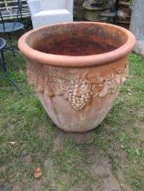 A large weathered terracotta circular tapered garden planter with repeating fruiting vine detail, 66