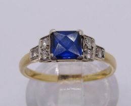 Art Deco 18ct ring with platinum setting, set with a French-cut sapphire between stepped diamond set