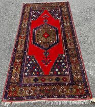 An Azerbaijan rug with a central medallion on a red ground, 210 x 107cm approx.