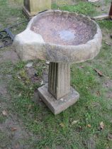 A weathered reconstituted stone bird bath, with shell, shaped bowl, 68 cm high, together with a pair