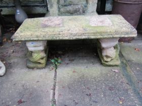 A weathered cast composition stone three sectional garden bench with stylised entwined dolphin