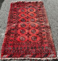 A Bokhara rug with two rows of small elephant foot guls on a faded pink ground, (as found one
