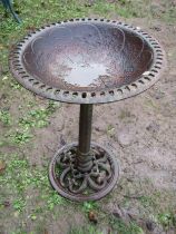 Weathered cast iron bird bath with circular pierced top, raised on a central pillar with pierced