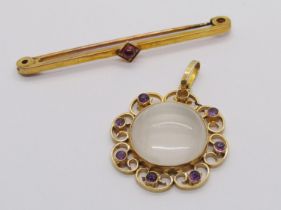 Edwardian style yellow metal cabochon moonstone pendant with scrolled frame set with amethysts (