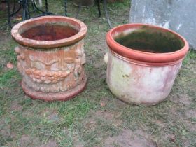 A weathered squat cylindrical terracotta planter with repeating raised relief winged cherub and