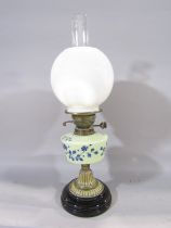 A Victorian oil lamps with a milk glass font decorated with blue flowers.