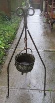 Antique cast iron cauldron with steel loop handle, hung on an ironwork stand (later used as a garden