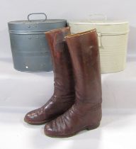 Two vintage oval tin hat boxes and a pair of vintage brown leather riding boots.