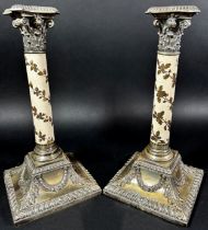 A pair of silver plated Corinthian column candlesticks with acorn and oak leaf to the china