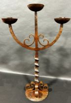 A cast iron three branch candlestick with a square twisted column raised on four scrolls and disc