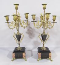 A pair of Victorian five branch brass candelabra raised on square marble and slate plinths with lion