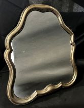 A silver metal dressing table mirror with a scroll shaped frame, with a wooden back and adjustable