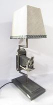 A novelty table lamp incorporating a vintage folding Kodak camera set on a two tier plinth,