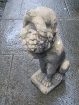 A weathered cast composition stone garden ornament in the form of a seated hound with basket of