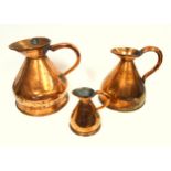 3 copper measuring jugs with riveted loop handles and on a raised foot, the smallest containing a