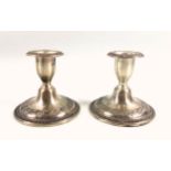 Pair of American white metal candlesticks, decorated with reserves of foliage and floral swags, by R