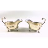 Pair of Edwardian silver sauceboats, of conventional form, with a shaped rim and flying scroll