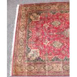 Persian carpet, the madder field with pendant medallion, spandrels and stylised floral decoration,