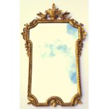 Wall mirror with a shaped upright plate, in a carved gilt wood gadrooned decorated frame, flanked by