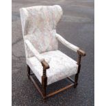 1930s German winged chair with scroll open arms, upholstered in patterned fabric, on turned legs and