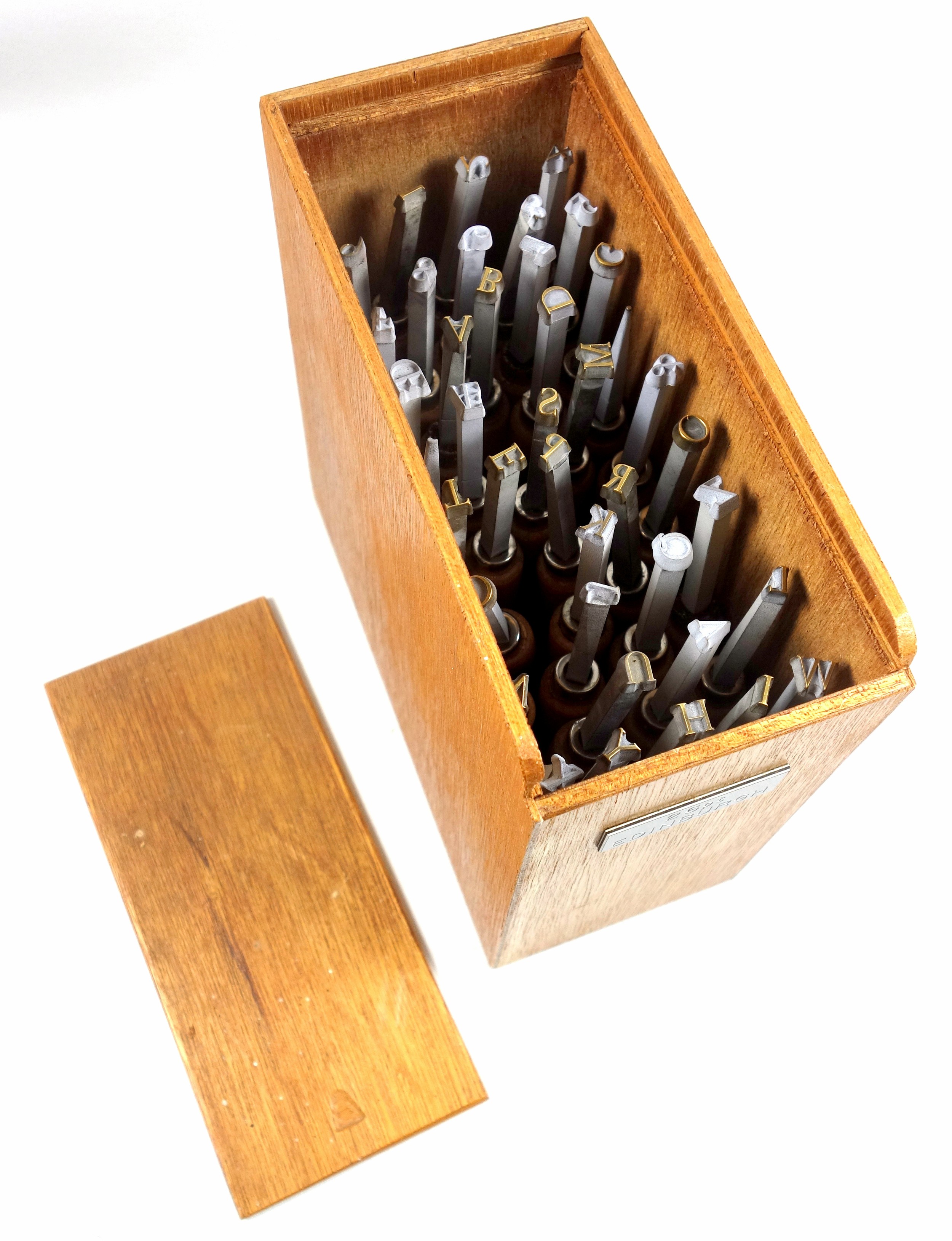 Wooden box containing 40 gold finishing hand tools comprising complete alphabet, numbers 1-9,