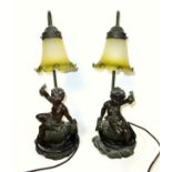 Pair of resin table lamps, each mounted with a putto, with a tinted glass shade, H.46.5cm. (2)