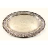 Thai white metal oval presentation dish, the rim embossed with scrolling decoration and 4 Buddhist